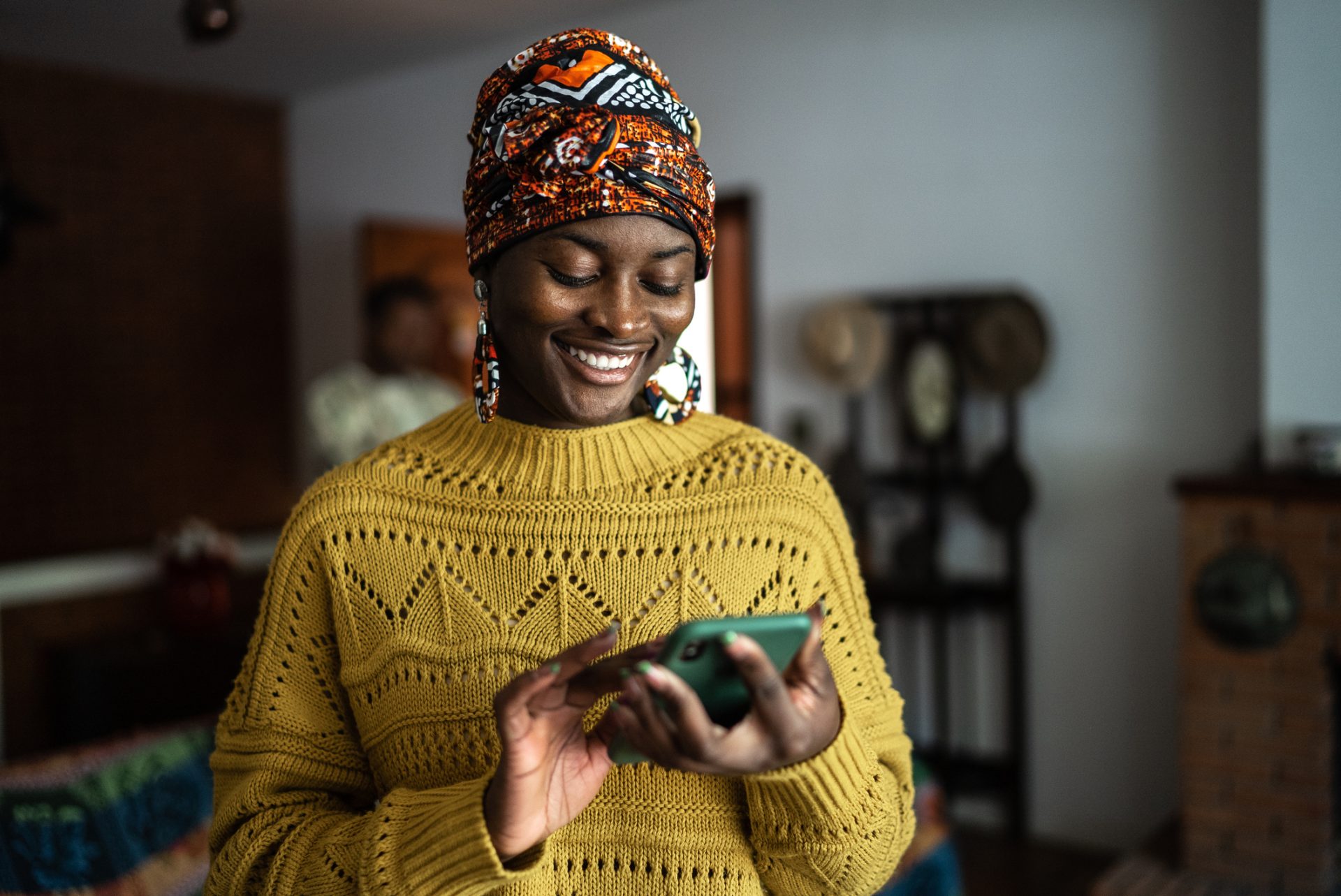 Happy woman in headband and sweater looking at phone screen